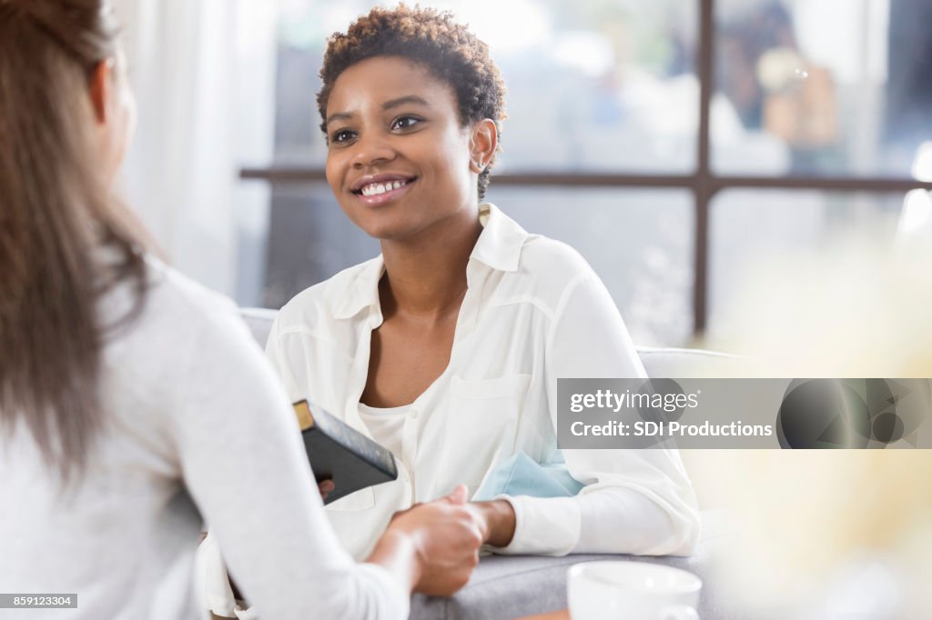 Unrecognizable woman gives her friend a Bible