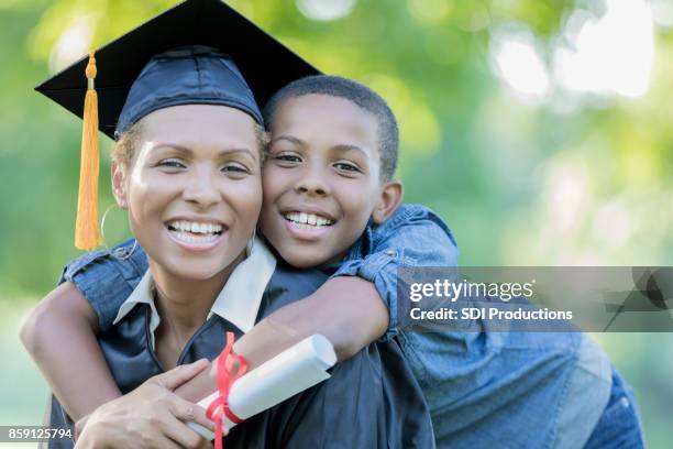 tween son poses with mom after her college graduation ceremony - son graduation stock pictures, royalty-free photos & images