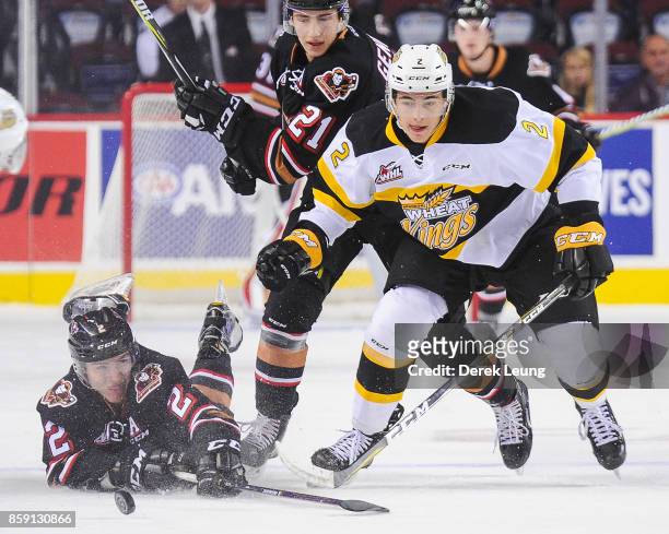 Jake Bean of the Calgary Hitmen loses the puck to Braden Schneider of the Brandon Wheat Kings during a WHL game at the Scotiabank Saddledome on...