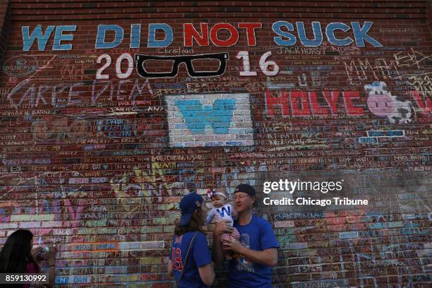 Shannon and Matthew Brokenshire of Elmhurst, Ill., hold up their baby daughter Mackenna near the Wrigley Field wall on the Waveland Avenue side of...