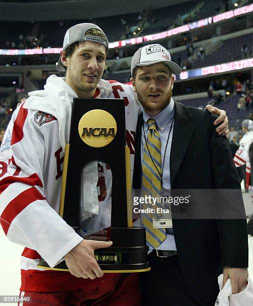Matt Gilroy of the Boston Terriers poses with his brother Kevin Gilroy and the national championship trophy after the NCAA Men's Frozen Four...