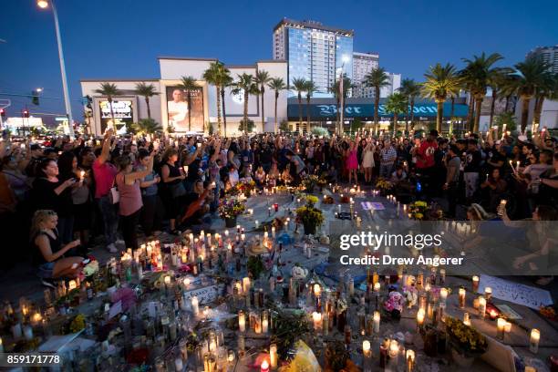Mourners hold their candles in the air during a moment of silence during a vigil to mark one week since the mass shooting at the Route 91 Harvest...