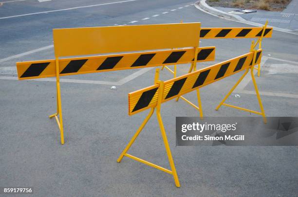yellow and black striped road traffic barricades on a suburban road t-intersection - barricada divisa - fotografias e filmes do acervo