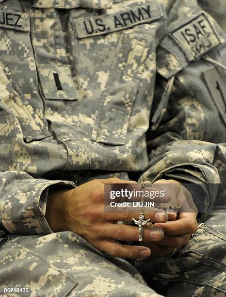 Soldier from 1st Infantry Division holds a rosary during an Easter Sunday Mass at the Raider Chapel in ISAF's Camp Bostick in Naray, in the eastern...