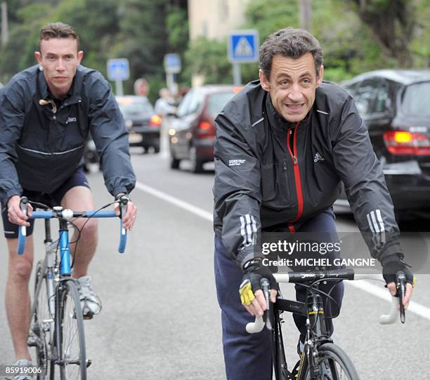 French president Nicolas Sarkozy leaves on his bike his wife, Carla Bruni-Sarkozy's residency on April 12, 2009 in the French city of Cavaliere,...