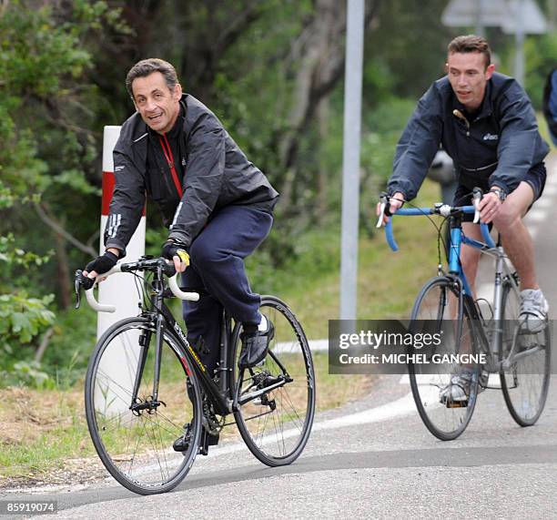 French president Nicolas Sarkozy arrives on his bike his wife, Carla Bruni-Sarkozy's residency on April 12, 2009 in the French city of Cavaliere,...