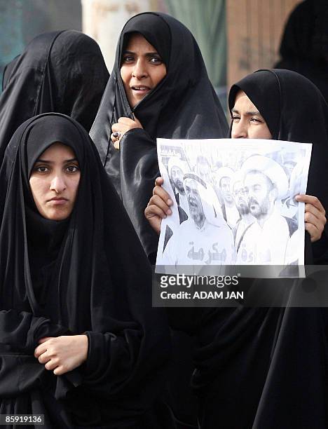 Bahraini Shiite women hold a picture of Hassan Mesheima , head of the Shiite-dominated opposition Haq movement, and Shiite cleric Mohammed al-Moqdad...