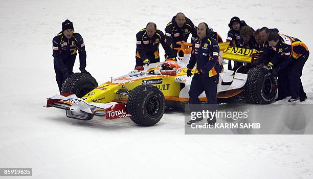 Renault's Formula One crew prepare Brazilian driver Nelson Piquet before taking the R29 for a drive during a promotional event for the car...