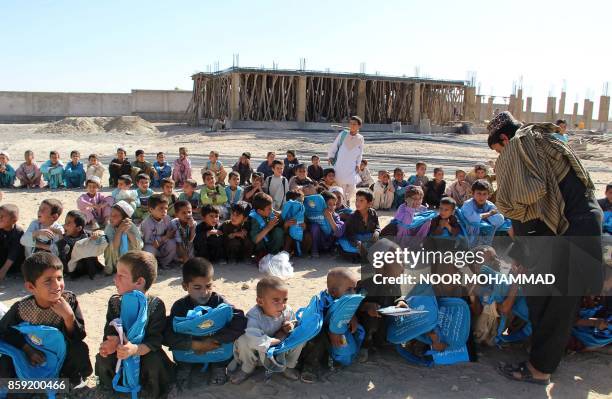 This picture taken on October 8, 2017 shows member of the United Nations Children's Fund distributing pens and bags to Afghan school boys at a school...