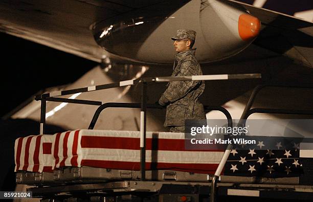 Member of a U.S. Air Force carry team stands next to two flag-draped transfer cases holding the remains of US Soldiers during a dignified transfer at...