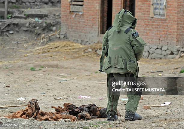 Member of the Indian Army Bomb Disposal Squad inspects the body of a militant before Indian soldiers open fire in the air to disperse thousands of...