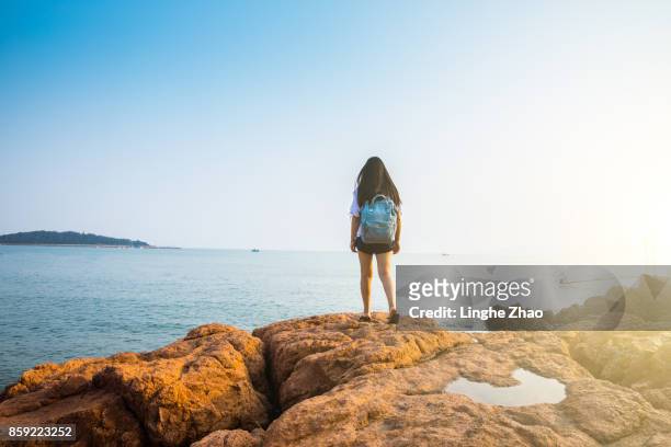 young woman standing by sea - linghe zhao photos et images de collection