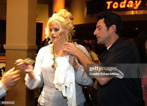 Anna Nicole Smith is helped by her attorney Howard K. Stern as she autographs money for a fan after attending the Chippendales show at the Rio Hotel...