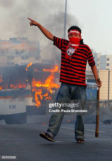 An anti-government protester signals as gun battles break out during violent protests on April 13, 2009 in Bangkok, Thailand. Anti-government...