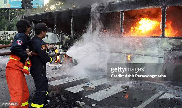 Firefighters attempt to put out a fire on a bus torched by supporters of former Prime Minister Thaksin Shinawatra during a protest on April 13, 2009...