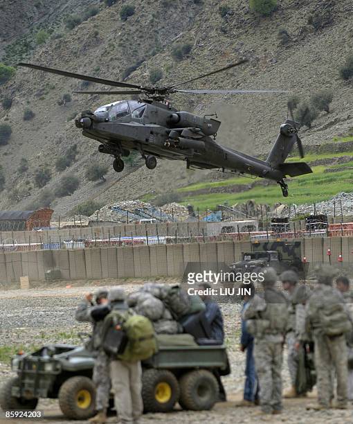 Army soldiers look at an AH-64 Apache helicopter landing at the ISAF's Camp Bostick in Naray, in Afghanistan's eastern Kunar province on April 13,...