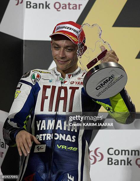 MotoGP rider Valentino Rossi raises his second place winner trophy on the podium of the MotoGP event at the Qatar Grand Prix in Losail near Doha on...