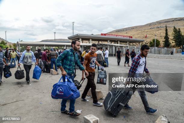 Syrian people carry their belongings as they cross the cilvegozu border gate to Turkish side on october 9, 2017 at Reyhanli district in Hatay. The...
