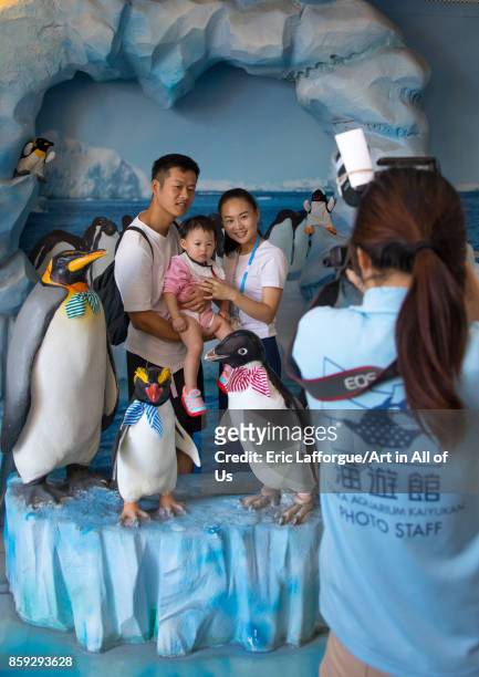 Family posing for a photo souvenir in the middle of fake penguins in Kaiyukan aquarium, Kansai region, Osaka, Japan on August 19, 2017 in Osaka,...