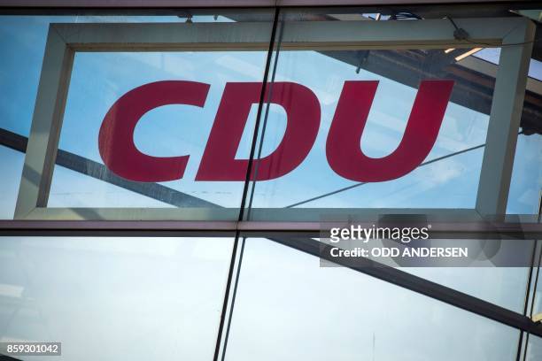 Picture taken on October 9, 2017 shows a board with the logo of the German Christian Democratic Union party and a flag of the European Union...