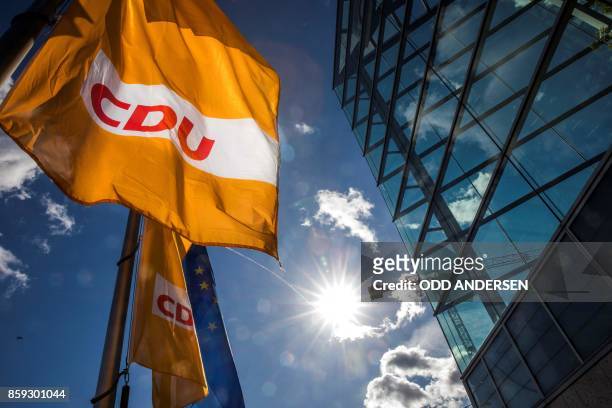 Picture taken on October 9, 2017 shows a flag with the logo of the German Christian Democratic Union party and a flag of the European Union...