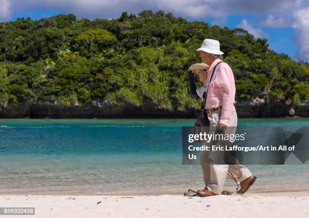 Old japanese couple walking along the tropical lagoon with clear blue water in Kabira bay, Yaeyama Islands, Ishigaki, Japan on August 28, 2017 in...