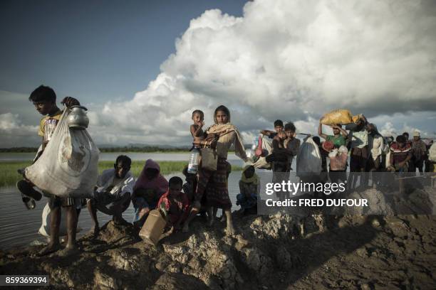 Rohingya refugees walk after crossing the Naf river from Myanmar into Bangladesh in Whaikhyang on October 9, 2017. A top UN official said on October...