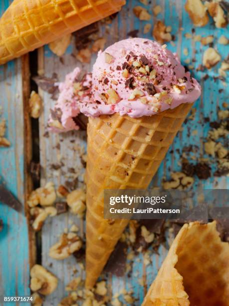 strawberry ice cream with chocolate and nuts in a waffle cone - serving scoop stock pictures, royalty-free photos & images