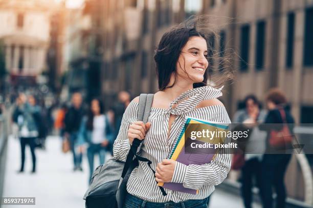 studente sorridente che cammina al vento - university foto e immagini stock