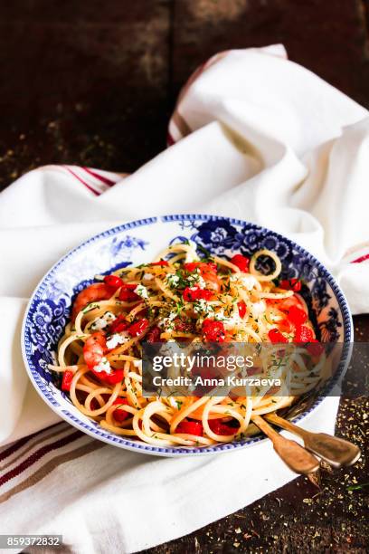 homemade whole wheat spaghetti pasta with roasted red bell pepper, prawns, salted greek feta cheese and dill in a bowl on a wooden table, selective focus - bell pepper stock-fotos und bilder