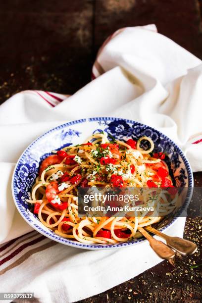 homemade whole wheat spaghetti pasta with roasted red bell pepper, prawns, salted greek feta cheese and dill in a bowl on a wooden table, selective focus - pasta tomato basil stockfoto's en -beelden