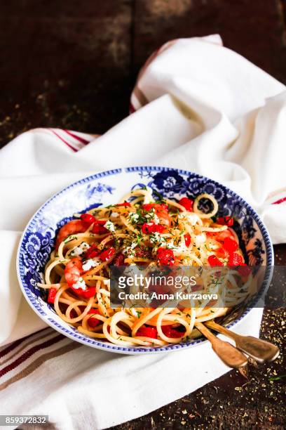homemade whole wheat spaghetti pasta with roasted red bell pepper, prawns, salted greek feta cheese and dill in a bowl on a wooden table, selective focus - feta stock pictures, royalty-free photos & images