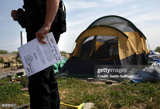 Sacramento police officer holds an eviction notice to be distributed to residents of a homeless tent city April 13, 2009 in Sacramento, California....