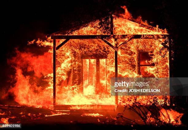 Flames overtake a structure as nearby homes burn in the Napa wine region in California on October 9 as multiple wind-driven fires continue to whip...