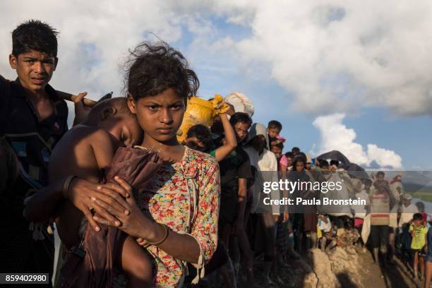 Thousands of Rohingya refugees fleeing from Myanmar walk along a muddy rice field after crossing the border in Palang Khali, Cox's Bazar, Bangladesh....