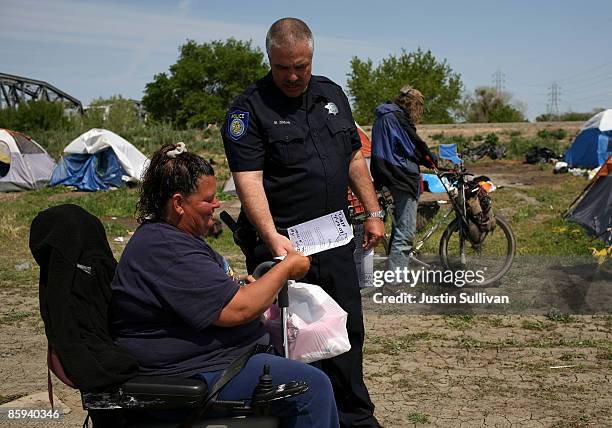 Sacramento police officer Mark Zoulas hands out eviction notices to residents at a homeless tent city April 13, 2009 in Sacramento, California....