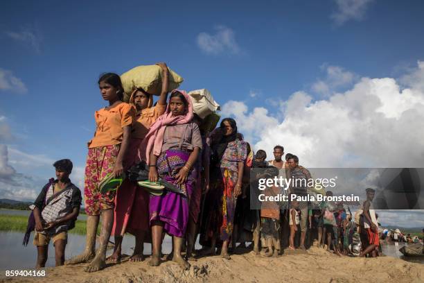 Thousands of Rohingya refugees fleeing from Myanmar walk along a muddy rice field after crossing the border in Palang Khali, Cox's Bazar, Bangladesh....