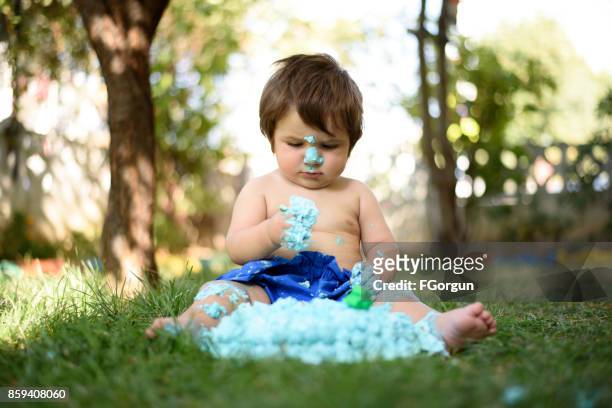 baby spelen met een taart tijdens cake smash verjaardagsfeestje - smash cake stockfoto's en -beelden