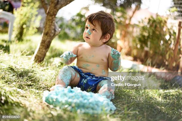 baby playing with a cake during cake smash birthday party - smash cake stock pictures, royalty-free photos & images