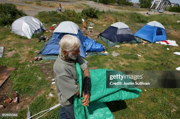 Don Gilsbach, a homeless man, folds a tarp as he packs up his belongings at a homeless tent city April 13, 2009 in Sacramento, California. Hundreds...