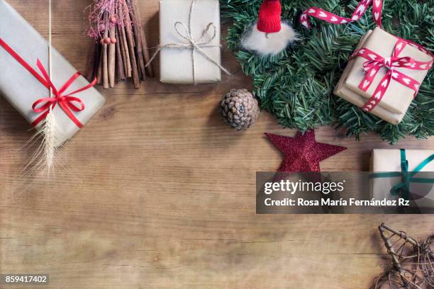 overhead of wrapped christmas presents, fir tree branches, and christmas ornaments on wooden background. copy space. - elf workshop stock pictures, royalty-free photos & images