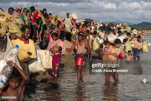 Thousands of Rohingya refugees fleeing from Myanmar walk along a muddy rice field after crossing the border in Palang Khali, Cox's Bazar, Bangladesh....