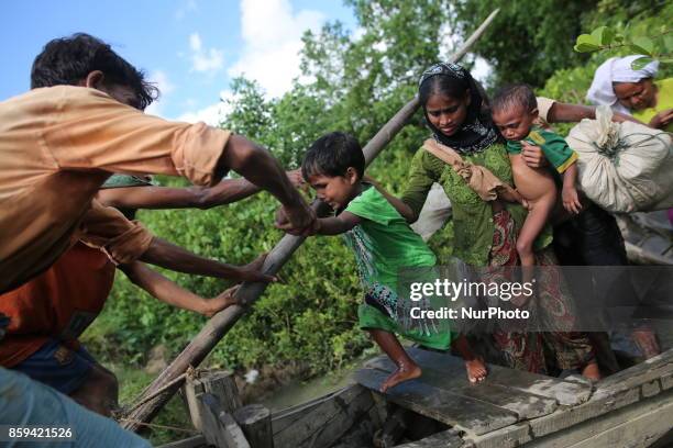 Rohingya Muslims, fled from ongoing military operations in Myanmars Rakhine state make their way through muddy water after crossing the...