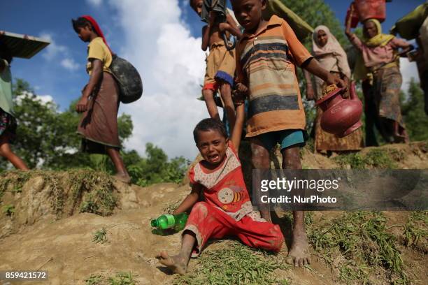 Rohingya Muslims, fled from ongoing military operations in Myanmars Rakhine state make their way through muddy water after crossing the...