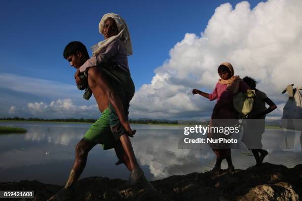 Rohingya Muslims, fled from ongoing military operations in Myanmars Rakhine state make their way through muddy water after crossing the...