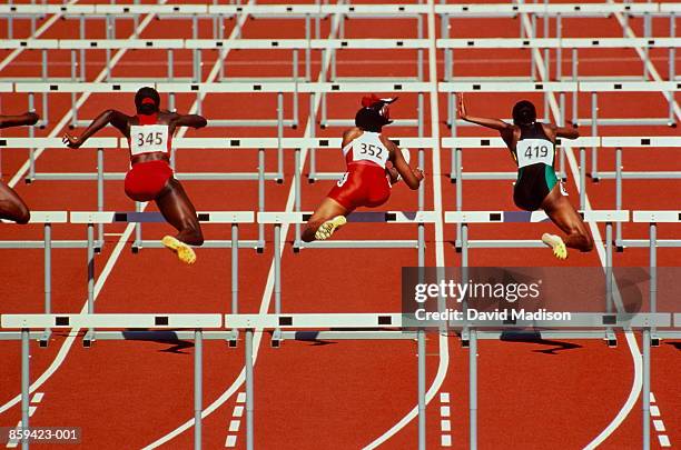 hurdles, female athletes in action, rear view - hordelopen atletiekonderdeel stockfoto's en -beelden