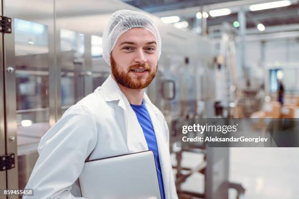 young smiling scientist with digital tablet posing in factory - hair net stock pictures, royalty-free photos & images