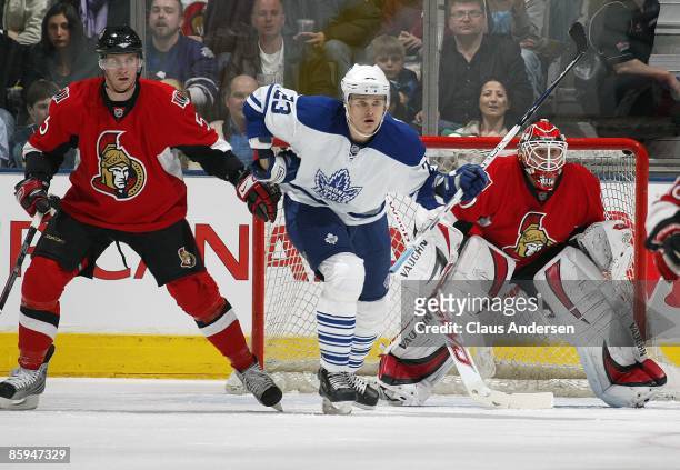 Alexei Ponikarovsky of the Toronto Maple Leafs looks to deflect a shot between Christoph Schubert and Brian Elliott of the Ottawa Senators in a game...