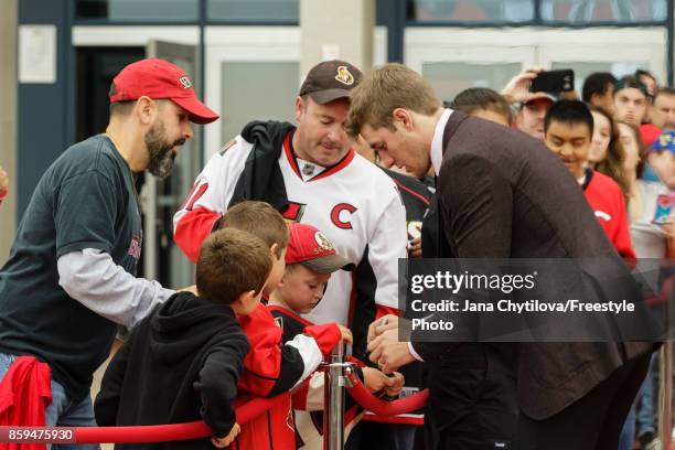 Kyle Turris of the Ottawa Senators signs an autograph on the red carpet prior to the start of a game against the Detroit Red Wings at Canadian Tire...