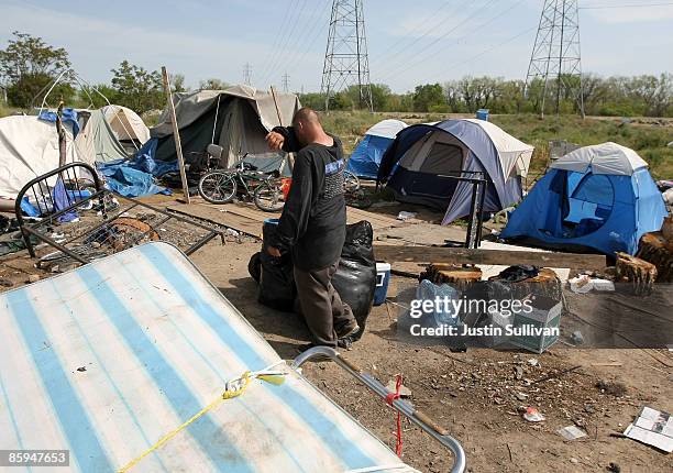 Homeless man wipes his forehead as he packs belongings at a homeless tent city April 13, 2009 in Sacramento, California. Hundreds of residents living...